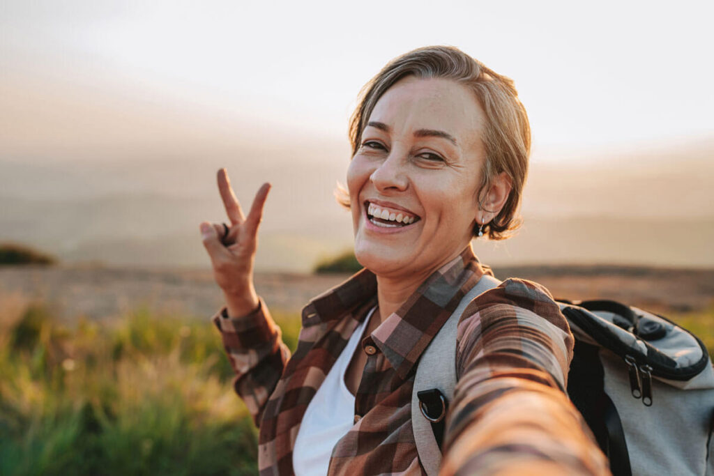 A female hiker smiles and throws a peace sign