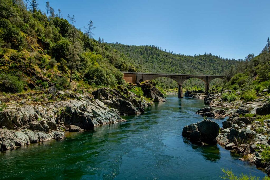 A multi-arched bridge extends over a calm, flowing river