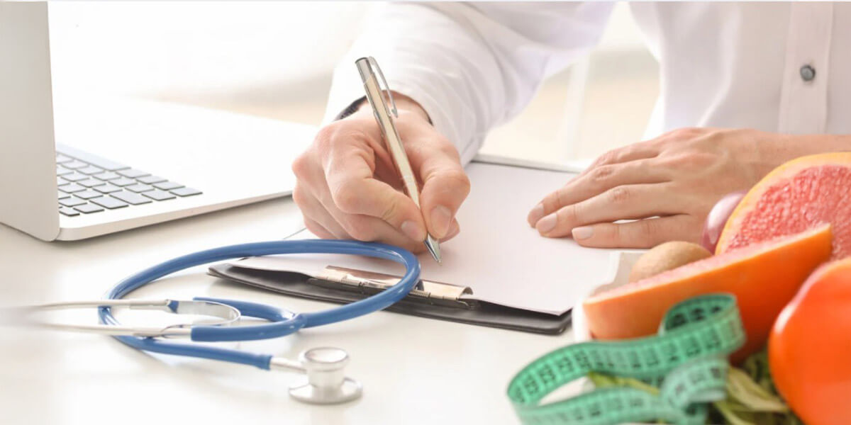 A healthcare professional writes notes beside medical tools and fresh foods, symbolizing structured treatment planning and holistic care options.